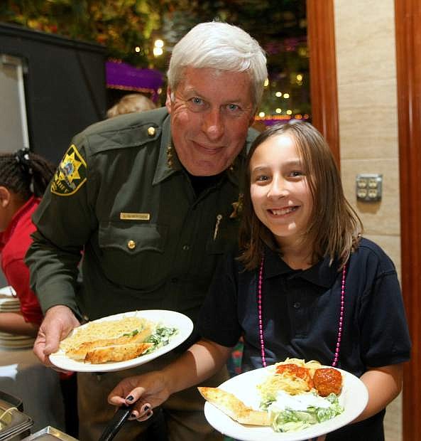 Carson City Undersheriff Steve Albertsen and 10-year-old Alexia Bourcier share a smile and fill their plates at the Cops and Kids Spaghetti Dinner on Tuesday.