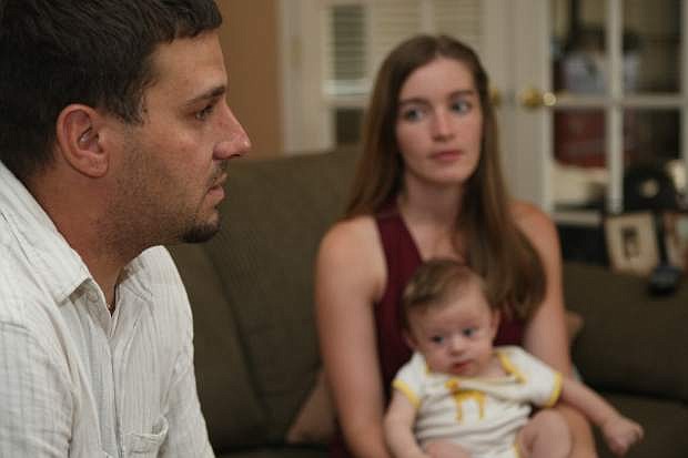 Megan Tingle, holding their son, Owen, listens to Daniel Tingle talk about his life after the military, at home on Aug. 21.
