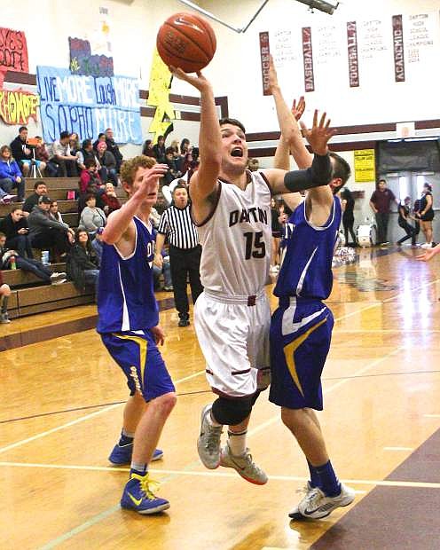 Senior Davis Winebarger (15) lunges past Lowry players Nathan Lutzow and Jacob Hale to put up a shot in a 64-41 Dust Devil loss on Saturday at Dayton High School.