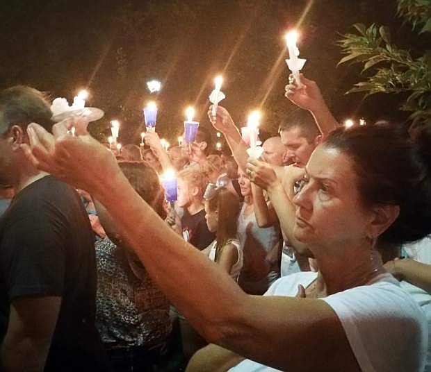 In this Saturday, Aug. 15, 2015 photo, mourners hold candles at a vigil on Nevada Capitol grounds in Carson City, Nev., honoring fallen Carson City deputy Carl Howell. Howell was killed earlier Saturday after a shootout during a domestic violence call. The suspect in the confrontation died on the scene. (AP Photo/Michelle Rindels)