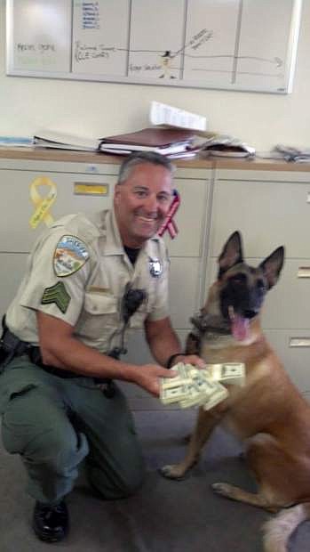 In this image released by the Humboldt County, Nev. Sheriff&#039;s Department in September 2013 and posted on their Facebook page, Sgt. Lee Dove poses with K-9 Zyla and $50,000 cash that was seized after a traffic stop for speeding. Dove is accused of stopping travelers on a lonely stretch of U.S. Interstate 80 and confiscating tens of thousands of dollars for the county without bringing charges, according to two federal lawsuits. Two men who were traveling alone through northern Nevada&#039;s high desert last year offer strikingly similar accounts of their stops by Dove near the town of Winnemucca, about 165 miles east of Reno. (AP Photo/Humboldt County Sheriff&#039;s Department)