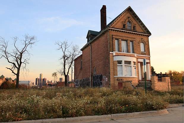 FILE - This Oct. 24, 2012 file photo shows a graffiti-marked abandoned home north of downtown Detroit, in background. Thousands of Detroit streetlights are dark, many more residents have fled. Donors are replacing ambulances that limped around for 200,000 miles.   Detroit&#039;s bankruptcy case is going to trial, Wednesday, Oct. 22, 2013, and the result will determine whether the city can reshape itself in the largest public bankruptcy filing in U.S. history.  (AP Photo/Carlos Osorio, File)