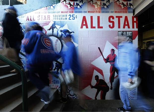 Baseball fans head to their seats past a mural of the 1947 All-Star Game program, on the 100th anniversary of the first baseball game at Wrigley Field, before a game between the Arizona Diamondbacks and Chicago Cubs, Wednesday, April 23, 2014, in Chicago.  (AP Photo/Charles Rex Arbogast)