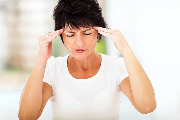 A mid-age woman is having a headache.