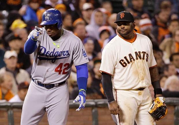 Los Angeles Dodgers&#039; Yasiel Puig, left, points to his dugout after a triple next to San Francisco Giants third baseman Pablo Sandoval during the eighth inning of a baseball game on Tuesday, April 15, 2014, in San Francisco. (AP Photo/Marcio Jose Sanchez)