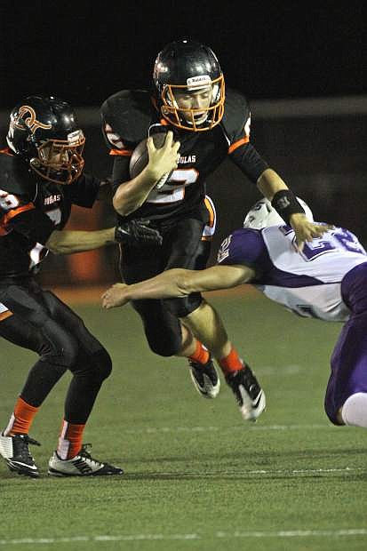 Douglas quarterback Bryce James leaps past a Spanish Springs defender Friday night at Douglas High. The Tigers won the game 23-13.