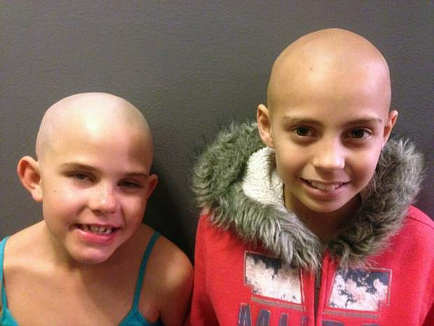 In this March 2014 photo provided by their families, Kamryn Renfro, 9, left, and Delaney Clements, 11, right, stand together for a photo in Grand Junction, Colo. shortly after Kamryn had her head shaved to support Delaney, who lost her hair after treatment for cancer. Kamryn was suspended from her public charter school in Grand Junction because a shaved head goes against the school&#039;s dress code. But the school quickly reversed the decision. (AP Photo)