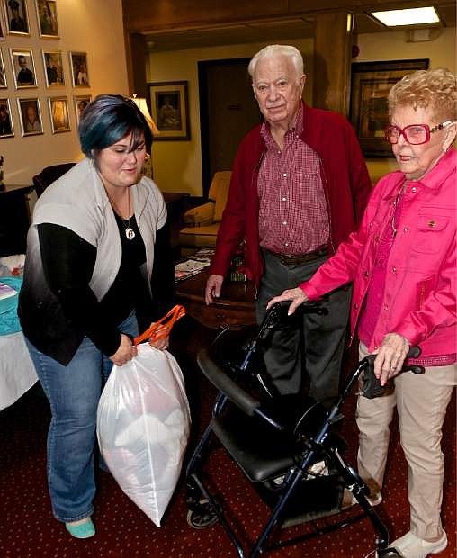 Traci Trenoweth of Advocates To End Domestic Violence accepts a bag of clothing from Bernie Schwartz and Eleanore Dunbar Friday at the Carson Plaza.
