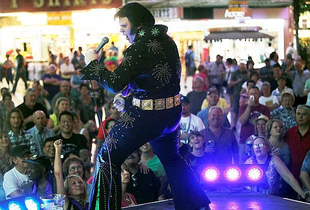 ADVANCE FOR WEEKEND EDITIONS SEPT. 14-15 - In this Sept. 3, 2013 photo, Tyler James performs as Elvis on the Fremont Street Experience First Street stage in Las Vegas. About 800 bookings have been made for Elvis collectively in the past year in Las Vegas. That number is down significantly, about 21 percent from 2011, but 2013 is tracking similar to 2012. (AP Photo/Las Vegas Review-Journal, Jason Bean) LOCAL TV OUT; LOCAL INTERNET OUT; LAS VEGAS SUN OUT