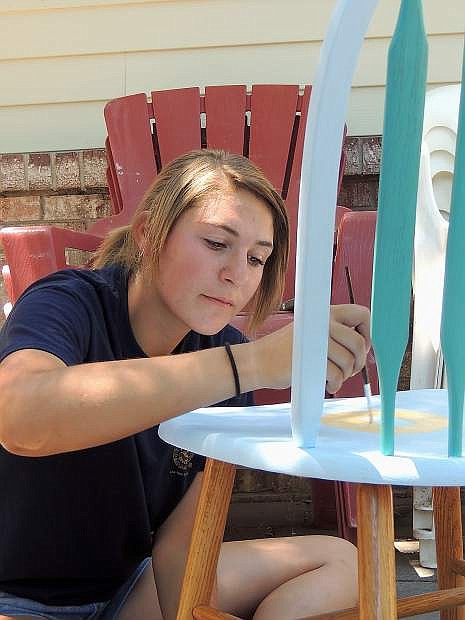 Alecia Ouellette, 17, a member of Capitol FFA, paints an ornamental chair Monday afternoon. The chairs will be auctioned off during the annual Concert on the Stars.