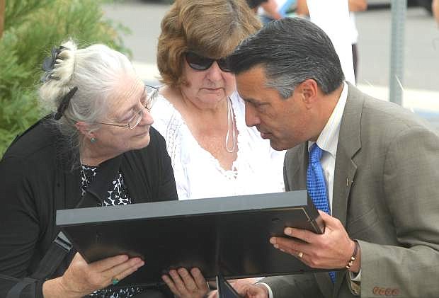 Gov. Brian Sandoval presents a State Flag and Proclamation to Susan Arding during the Nevada Department of Transportation Memorial Star Dedication to her son Ron Raiche, Jr. on Monday.