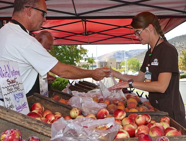 CNA/EKG Tech Cassandra Aveiro purchases fresh peaches from Erik Kisbye of R. Schletewitz Family Farms of Sanger, Calif. at the farmer&#039;s market Thursday at Carson-Tahoe Medical Center.