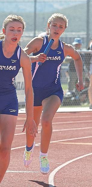 Carson High&#039;s Athena Favero, left, hands the batton off to Sahara Winder during the 800-meter relay. The NIAA Division I track trials kick off today at Carson High.