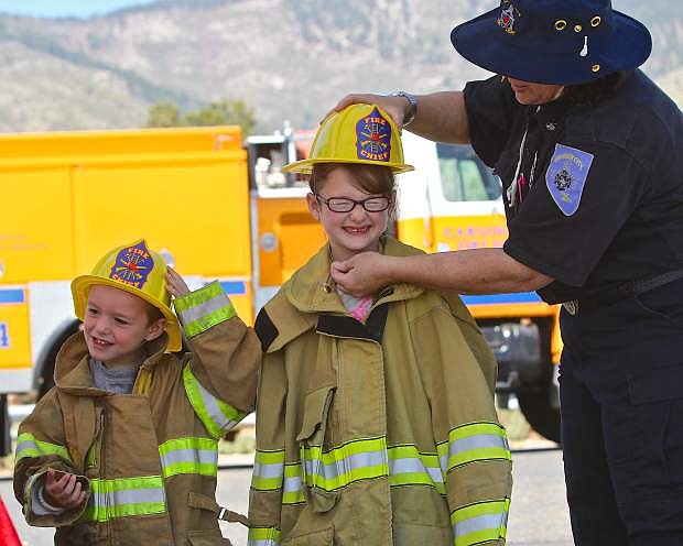 Grayson Blankenship, 4, and his sister Cate, 6, try on fire turnouts and helmets with the help of Carson City Fire Inspector Lee Ann Horton at the fire department open house at WNC Saturday morning. As a part of Nevada Wildfire Awareness month, the fire department hosted the event so that residents can interact with the department, see the equipment and see what programs are available to assist them in preparing for wildfire threats.