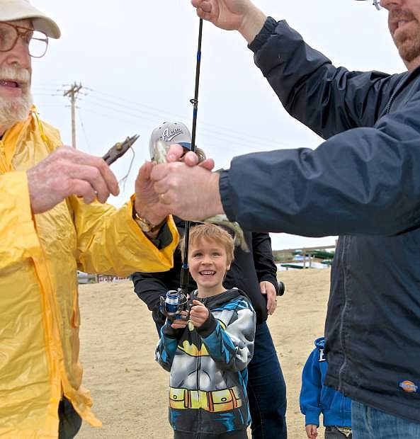 6-year-old Darren Plain reels in a trout with the help of his dad Adam and expert fisherman Vic Burgard Saturday morning at the Tom Brooks Memorial Fishing Day at Baily Pond. The Carson City Host Lions Club sponsored the event with help from other organizations.