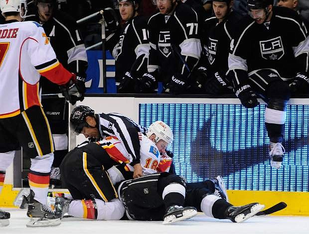 Linesman Jay Sharrers (57) attempts to break up a fight between Calgary Flames center Matt Stajan (18) and Los Angeles Kings right wing Dustin Brown, bottom, during the second period of an NHL hockey game, Saturday, Nov. 30, 2013, in Los Angeles. (AP Photo/Gus Ruelas)