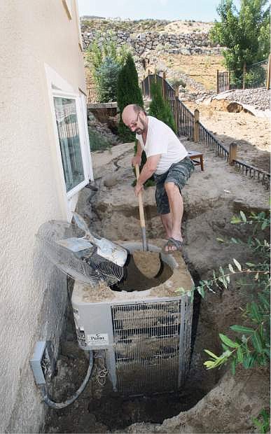 Roman Friedman, who lives on Long Drive in Sunridge digs out his air conditioner on Monday after it was buried in nearly five feet of sand that washed down the hillside behind his home during Sunday&#039;s severe thunderstorm,