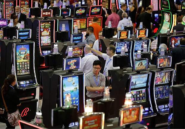 In this Sept. 30, 2015 file photo, people look at slot machines at the Ballys Technology booth during the Global Gaming Expo in Las Vegas.