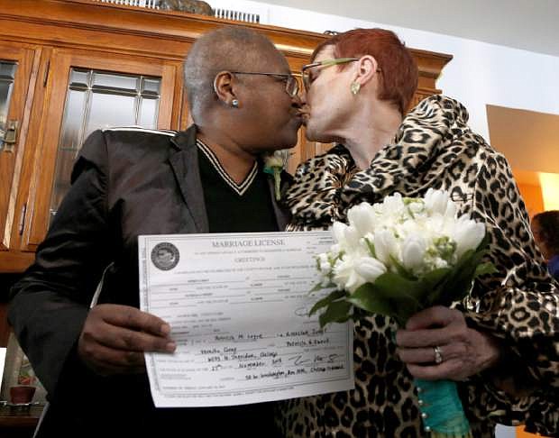 Holding their Illinois marriage license, Vernita Gray, left, and Patricia Ewert kiss after they were married by Cook County Judge Patricia Logue, the first gay marriage in Illinois, at the couple&#039;s home Wednesday, Nov. 27, 2013, in Chicago. U.S. District Judge Thomas Durkin on Monday, Nov. 25, 2013, ordered the Cook County clerk to issue an expedited marriage license to Gray and Ewert before the state&#039;s gay marriage law takes effect in June 2014, because Gray is terminally ill. (AP Photo/Charles Rex Arbogast)