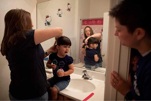 FILE - In this April 29, 2012 file photo, Megan Lanz, left, combs her 3-year-old daughter, Jordan&#039;s hair, as partner Sara Geiger watches before the three leave for a picnic in a park, in Las Vegas. The same-sex marriage debate returns Monday Sept. 8, 2014, to the same San Francisco federal appeals court that has already issued two significant rulings in support of gay weddings. The 9th U.S. Circuit Court of Appeals will consider separate lawsuits stemming from gay marriage bans in Idaho, Nevada and Hawaii. So far, 19 states and Washington D.C. now allow gay marriages even though the U.S. Supreme Court has yet to directly rule on whether states can impose bans. (AP Photo/Julie Jacobson, file)