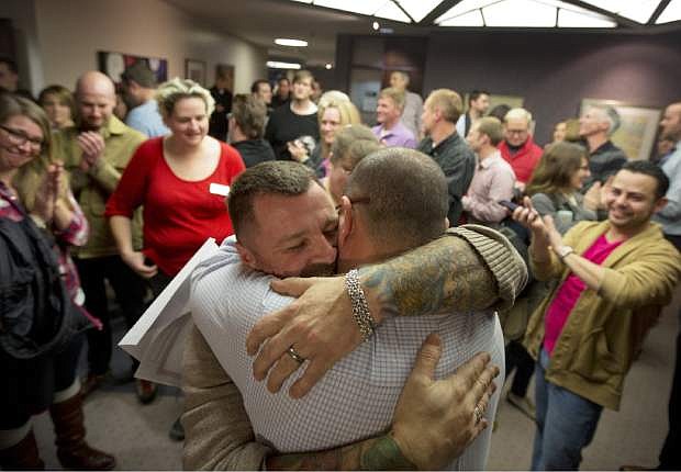 FILE - In this Friday, Dec. 20, 2013 file photo, Chris Serrano, left, and Clifton Webb embrace after being married, as people wait in line to get licenses outside of the marriage division of the Salt Lake County Clerk&#039;s Office in Salt Lake City. A federal judge on Monday, Dec. 23, 2013 is set to consider a request from the state of Utah to block gay weddings that have been taking place since Friday when the state&#039;s same-sex marriage ban was overturned. (AP Photo/Kim Raff, File)