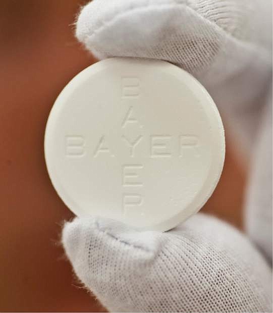 In this photo taken July 6, 2009 worker Roland Ulbrich presents an Aspirin pill made for Italy at the pharmaceutical plant of the Bayer Bitterfeld company in Bitterfeld-Wolfen, eastern Germany.  Germany&#039;s Bayer AG says it plans to buy U.S. pharmaceutical company Merck &amp; Co. Inc.&#039;s consumer care business, whose products include the Coppertone suncare range, Claritin allergy medicine and the Dr. Scholl&#039;s footcare products, for US$ 14.2 billion. (AP Photo/Eckehard Schulz)