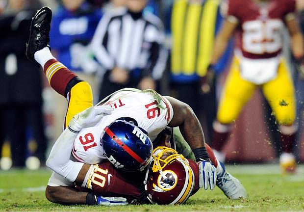 Washington Redskins quarterback Robert Griffin III (10) is sacked by New York Giants defensive end Justin Tuck (91) during the second half of an NFL football game Sunday, Dec. 1, 2013, in Landover, Md. The Giants won 24-17. (AP Photo/Nick Wass)