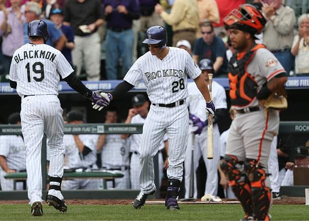Colorado Rockies&#039; Charlie Blackmon, left, is congratulated after his solo home run by Nolan Arenado as San Francisco Giants catcher Hector Sanchez looks away in the fourth inning of a baseball game in Denver on Wednesday, April 23, 2014. (AP Photo/David Zalubowski)