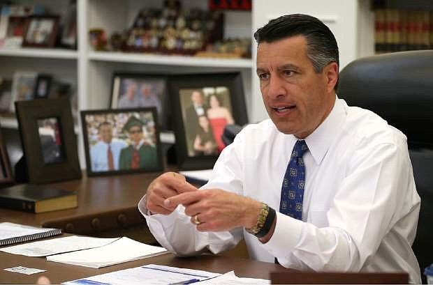 FILE - In this April 17, 2015, file photo, Nevada Gov. Brian Sandoval sits in his office at the Capitol in Carson City, Nev.  Sandoval is heading out on a trade mission to Europe including England, Ireland, Germany, Poland and Italy. (AP Photo/Cathleen Allison, File)