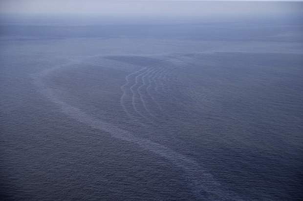 This March 31, 2015 photo shows an oil sheen drifting from the site of the former Taylor Energy oil rig in the Gulf of Mexico, off the coast of Louisiana. The AP&#039;s review of more than 2,300 pollution reports since 2008 found they didn&#039;t match official accounts of a diminishing leak. In fact, the reports show a dramatic spike in sheen sizes and oil volumes since Sept. 1, 2014. (AP Photo/Gerald Herbert)