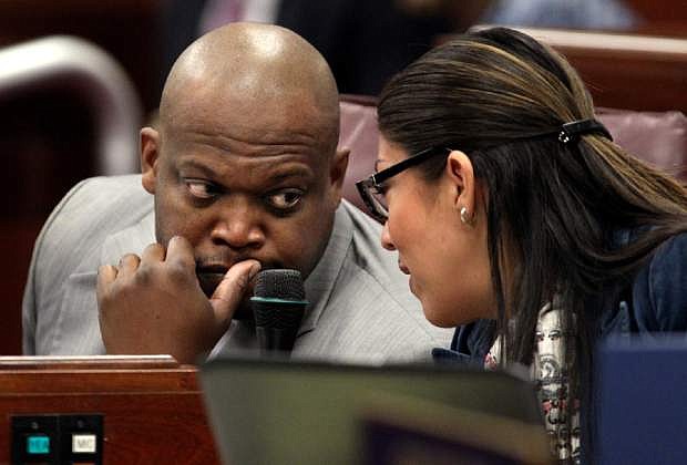 Nevada Assembly Democrats William Horne and Lucy Flores work on the Assembly floor at the Legislative Building in Carson City, Nev., Monday, March 11, 2013. Horne introduced a measure Monday that mandates background checks for private gun sales, bans the possession of armor-piercing bullets and imposes a tax on all firearm sales with proceeds benefiting mental services. (AP Photo/Cathleen Allison)