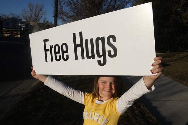 Chloe Clark, 8, displays a sign at the Happiness Sprinkling Project on Monday in front of the Legislature building.