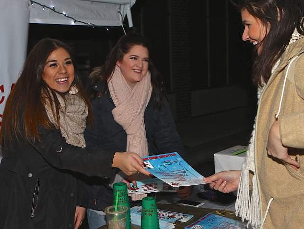 Sophia Flanagan and Alexis Lequerica, UNR volunteers, sell a Holiday Crawl admisssion to Tiffany Renkenberger Saturday night in downtown Carson City.