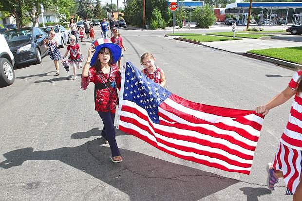 8-year-old Eva Lindbloom parades down Curry Street holding the American flag Thursday in Carson City.