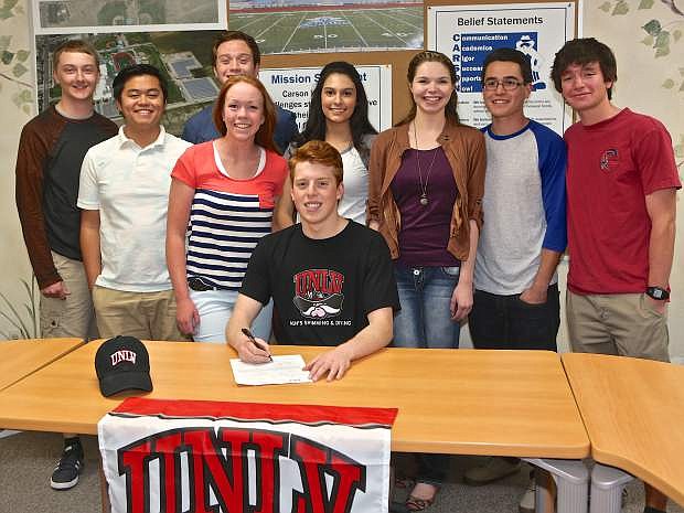 Carson senior Dagen Kipling signs his letter of intent to swim for UNLV Thursday with the support of some of his CHS teammates.