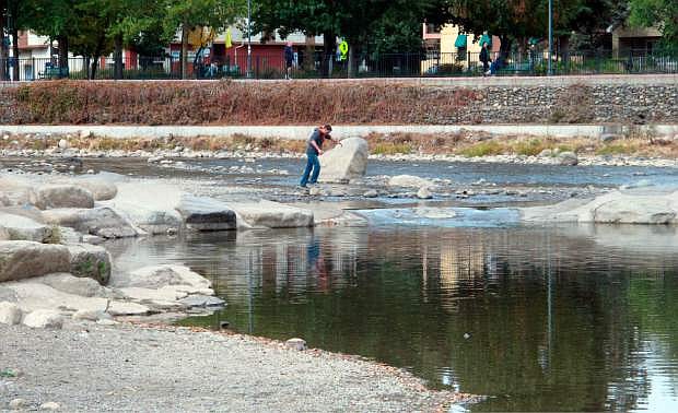 A man crosses the Truckee River in Reno. Nev. on Friday, Oct. 17, 2014, over shallow rocks not usually above the surface at the mouth of a whitewater kayaking park. Lake Tahoe dropped below its natural rim level for the first time in five years this week, which cut off flows into the river as it meanders 30 miles down the Sierra and through Reno on a 90-mile journey to Pyramid Lake. (AP Photo/Scott Sonner)