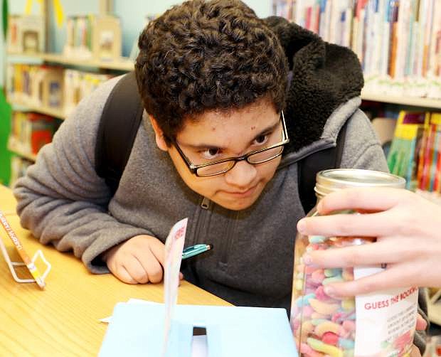 Fourteen-year-old Aaron Portillo makes a guess of how many bookworms are in the jar on Thursday at the Carson City Library. The library hosted events and displays including a scavenger hunt, book buffet, guess the librarian baby pictures and guess the bookworms in celebration of National Library Week with the American Library Association.