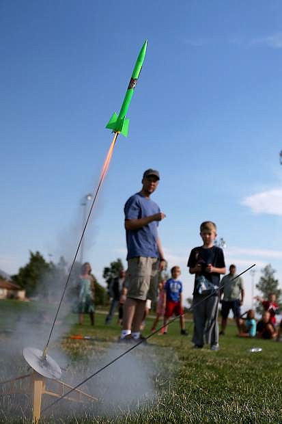 Kevin Clifford, with the Reno Rocketry Club, helps Hayden Brundage, 6, launch a rocket during a Carson City Library Summer Reading Program event at Edmonds Sports Complex on Saturday. Wild Things, Inc. will be at the library 5:30 and 6:30 p.m. today, bringing a  live kangaroo and alligtor to the Digitorium.