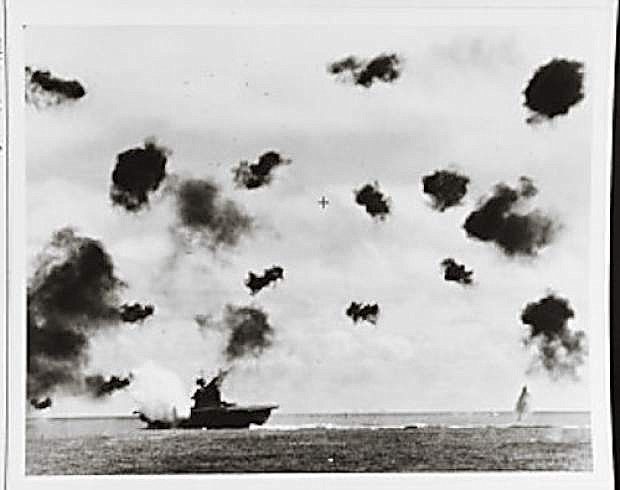 USS Yorktown (CV 5) is hit on the port side, amidships, by a Japanese Type 91 aerial torpedo during the mid-afternoon attack by planes from the carrier Hiryu, June 4, 1942. Photographed from USS Pensacola (CA 24). Yorktown is heeling to port and is seen at a different aspect than in other views taken by Pensacola, indicating that this is the second of the two torpedo hits she received.