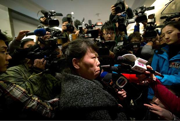 A Chinese relative of passengers aboard a missing Malaysia Airlines plane is surrounded by media as she answers questions about how families are being compensated outside a hotel room set aside for relatives or friends of passengers aboard the missing airplane in Beijing, China Tuesday, March 11, 2014.  Authorities hunting for the missing Malaysia Airlines jetliner expanded their search on land and sea Tuesday, reflecting the difficulties in finding traces of the Boeing 777 more than three days after it vanished with 239 people on board.   (AP Photo/Andy Wong)