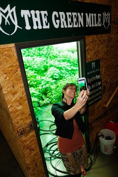 In this photograph taken Saturday, April 25, 2015, Reno, Nv., consultant Rebecca Gasca stops to take a &quot;selfie&quot; photograph in front of the doorway leading to &quot;The Green Mile,&quot; the main grow room in a marijuana retail and grow operation in northeast Denver, as a contingent of Nevada lawmakers, their staffers and a handful of lobbyists toured the facility. Nevada lawmakers who were on the fact-finding mission say that they came away quite impressed with the level of refinement that has been achieved in the recreational marijuana industry in Colorado since its inception. (AP Photo/David Zalubowski)