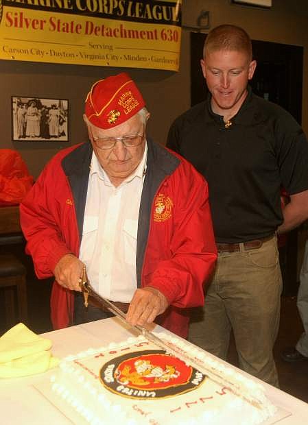 Following Marine Corps tradition, Joe Gabiola. 85, slices a piece of cake for 28-year-old Matt Thomasson during a celebration of the U.S. Marine Corps 240th birthday at the Westside Pour House on Tuesday night. Costco designed and donated the cake.