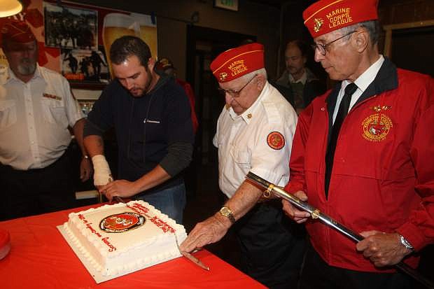 Marine Corps Silver State Detachment #630 Commandant Gary Armstrong, right, looks on as the oldest Marine Joe Gabiola, 84 and youngest Marine Robert Grainer, 28, use a sword to slice a cake to celebrate the 239th birthday of the Marine Corps on Monday at the Westside Pour House.