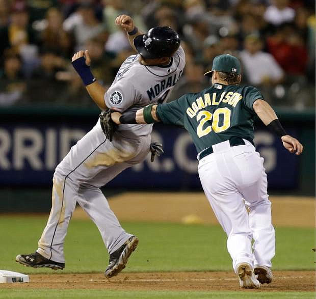Seattle Mariners&#039; Kendrys Morales, left, is tagged out by Oakland Athletics third baseman Josh Donaldson in the seventh inning of a baseball game Monday, Aug. 19, 2013, in Oakland, Calif. Morales was trying to advance on a hit by Justin Smoak. (AP Photo/Ben Margot)
