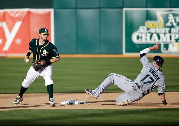 Oakland Athletics second baseman Eric Sogard, left, forces out Seattle Mariners&#039; Justin Smoak (17) at second base on a ground ball by James Jones during the seventh inning of a baseball game on Wednesday, May 7, 2014, in Oakland, Calif. (AP Photo/Marcio Jose Sanchez)