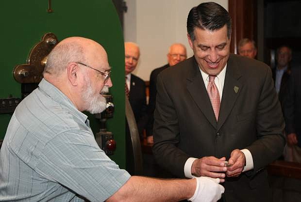 Ken Hopple gives Nevada Gov. Brian Sandoval the first sesquicentennial medallion minted on Wednesday afternoon at the Nevada State Museum.