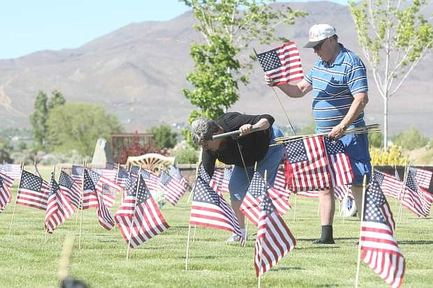 Four-year-old Natalie Duenas helps post flags at Lone Mountain Cemetery on Friday afternoon.