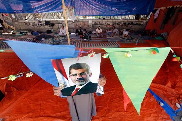 A supporter of Egypt&#039;s ousted President Mohammed Morsi hangs his poster at a tent in Nahda Square, where protesters have installed their camp near Cairo University in Giza, southwestern Cairo, Egypt, Monday, Aug. 12, 2013. Egyptian authorities on Monday postponed a move to disperse two Cairo sit-ins by supporters of the country&#039;s ousted president to &quot;avoid bloodshed,&quot; an official said, as Islamist supporters stepped up rallies to demand his return to power. (AP Photo/Amr Nabil)