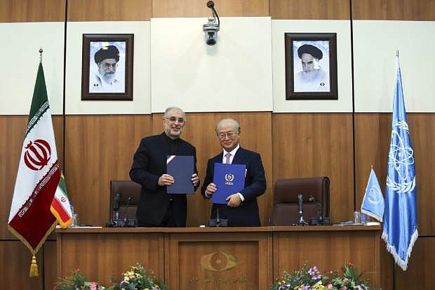 Head of Iran&#039;s Atomic Energy Organization Ali Akbar Salehi, left, and International Atomic Energy Agency (IAEA) Director General Yukiya Amano, pose for a photo under portraits of Iran&#039;s supreme leader, Ayatollah Ali Khamenei, left, and Iran&#039;s founder of Islamic Republic, Ayatollah Ruhollah Khomeini, right, following their meeting in Tehran, Iran, Monday, Nov. 11, 2013. Iran and the U.N. nuclear watchdog agency have reached a roadmap deal for cooperation during talks in Tehran Saturday that expands the monitoring of the country&#039;s nuclear sites. (AP Photo/ ISNA, Mehdi Ghasemi)