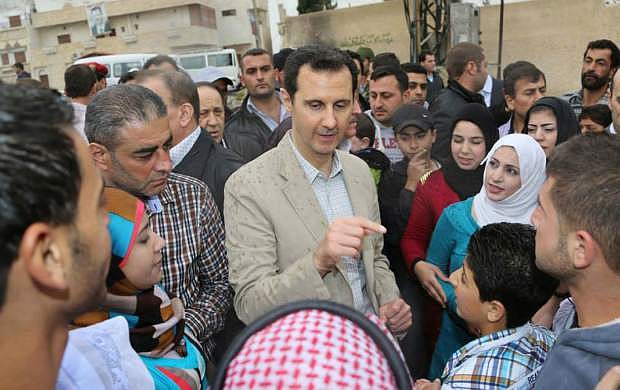 In this photo taken on Sunday, April 20, 2014 and released by the Syrian official news agency SANA, Syrian President Bashar Assad, center, speaks with Syrian citizens during his visit to Ain al-Tineh village, near Damascus, Syria. Assad visited on Sunday a historic Christian village his forces recently captured from rebels, state media said, as the country&#039;s Greek Orthodox Patriarch vowed that Christians in the war-ravaged country &quot;will not submit and yield&quot; to extremists. The rebels, including fighters from the al-Qaida-affiliated Nusra Front, took Maaloula several times late last year. (AP Photo/SANA)